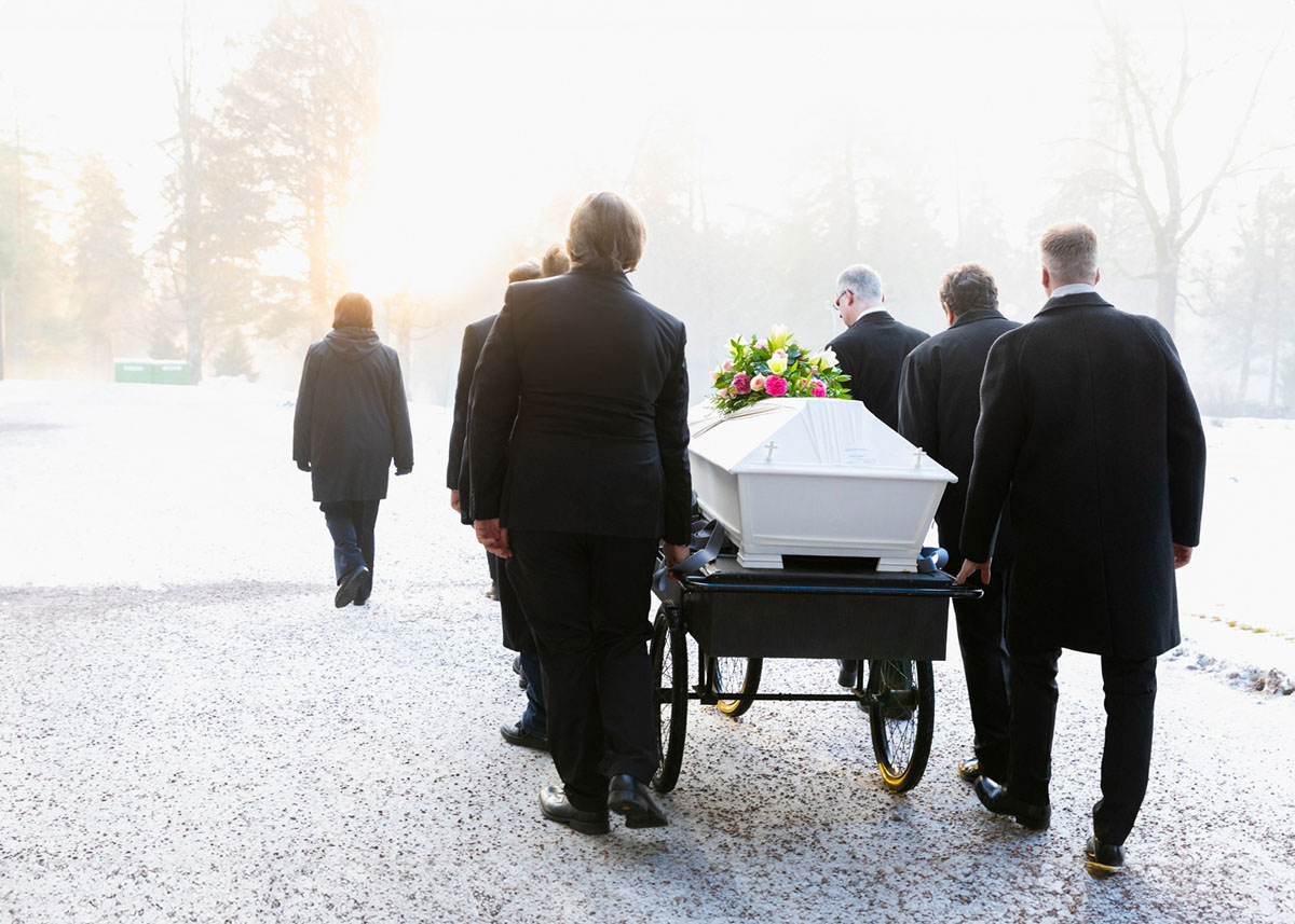 Kantajat arkun kanssa hautajaisissa